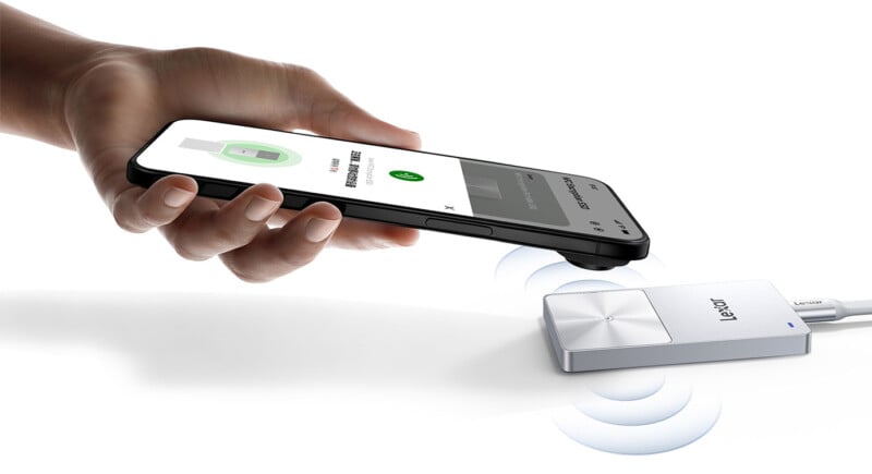 A hand holds a smartphone near a Lexar external device, showing wireless data transfer or charging in progress. The Lexar device is connected to a cable.