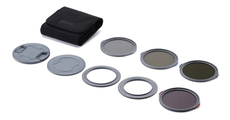 A camera lens filter kit is displayed, including several circular filters, two lens caps, two metal rings, and a black carrying pouch, all arranged on a white background.