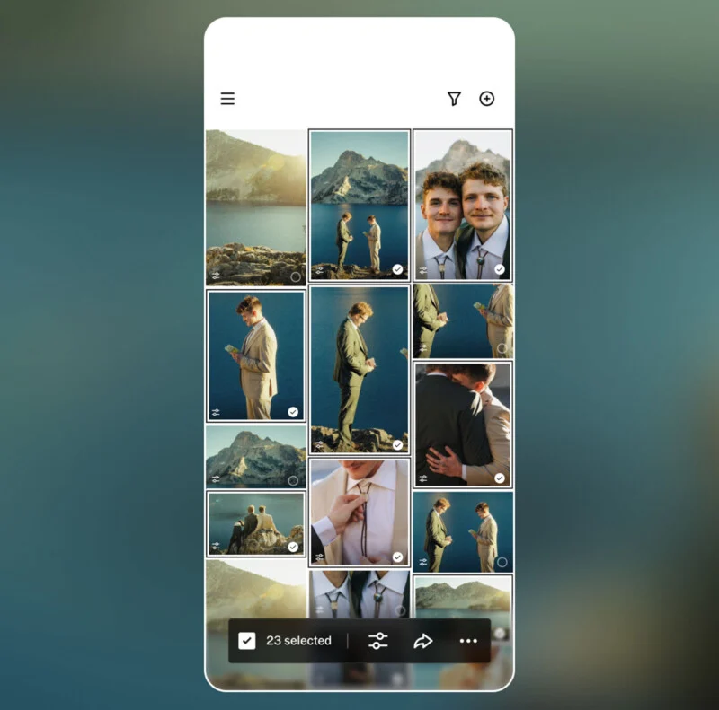 A smartphone screen shows a photo gallery with images of two men in suits by a lake and mountains, embracing, smiling, and standing together; 23 photos are selected at the bottom.