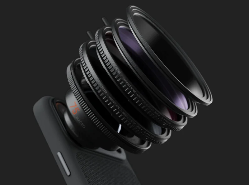 A smartphone camera with multiple lens elements and rings exploded outward, showing the internal layers of the lens assembly, set against a dark background.