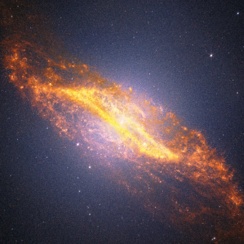 A bright, colorful spiral galaxy glows with vivid yellow, orange, and red clouds of gas and dust, surrounded by countless white stars against the dark background of space.