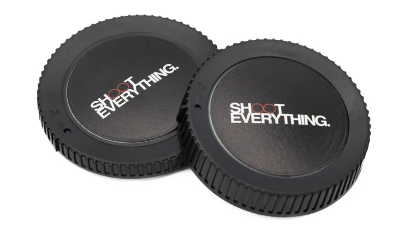 Two black camera body caps with the text "SHOOT EVERYTHING." printed in white and red on the center, resting on a white background.