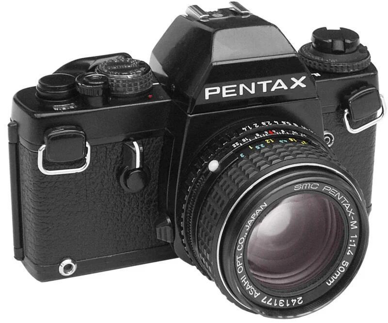 A black Pentax 35mm film SLR camera with an SMC Pentax-M 50mm f/1.4 lens attached, viewed from the front-left angle.