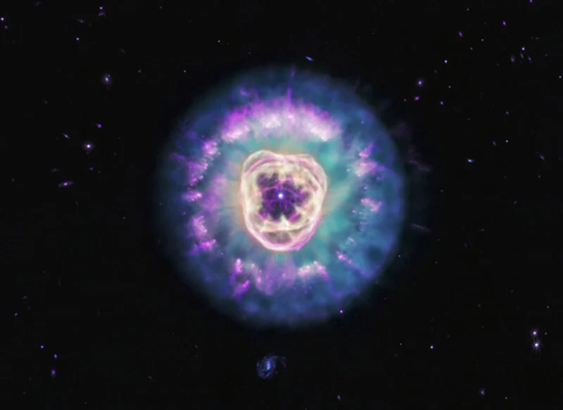 A vibrant, glowing planetary nebula with concentric rings of purple, blue, and gold gas surrounding a bright central star.