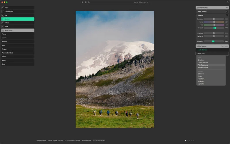 A photo editing software interface displays a mountain landscape with hikers in a meadow, surrounded by editing panels and adjustment sliders.