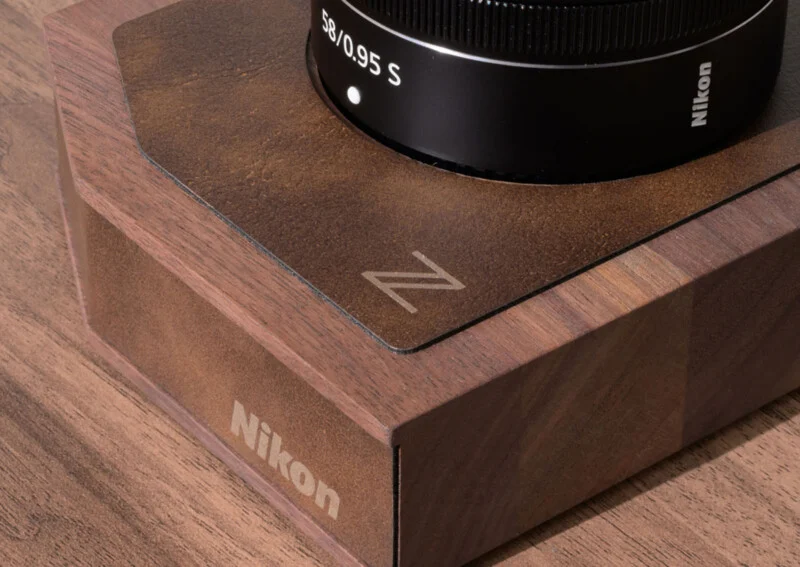 A Nikon 58/0.95 S lens sits on a wooden display base featuring the Nikon logo and a Z emblem.