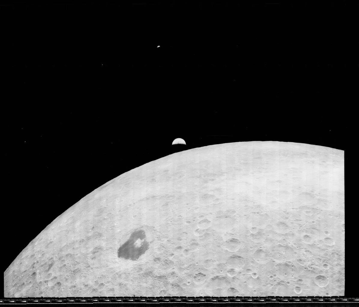 A black-and-white view of the Moon's cratered surface with the Earth appearing as a crescent in the dark sky above.
