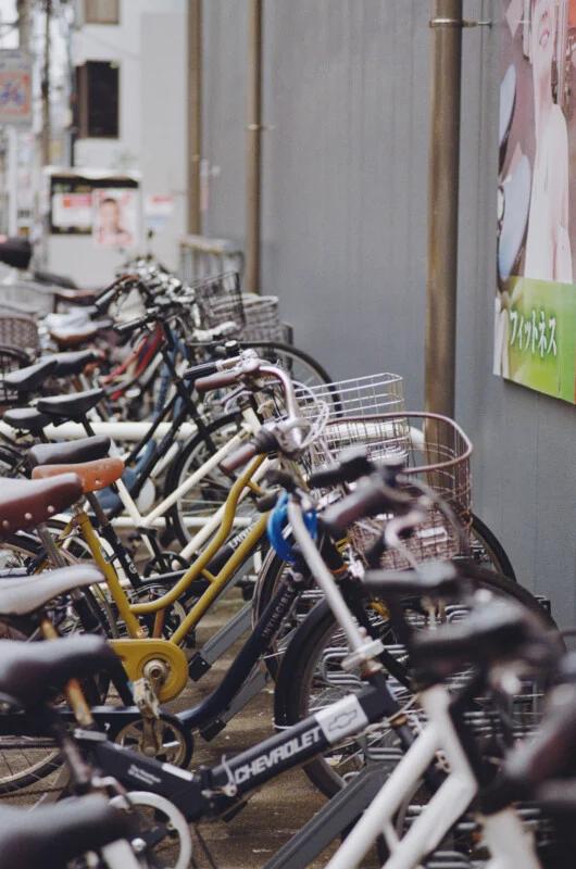 A row of bicycles parked in a line along a gray wall, with a Chevrolet-branded bike in the foreground.