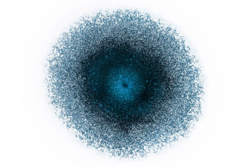 A circular, textured blue shape with a dark, dense center that fades into a lighter, speckled edge against a white background.