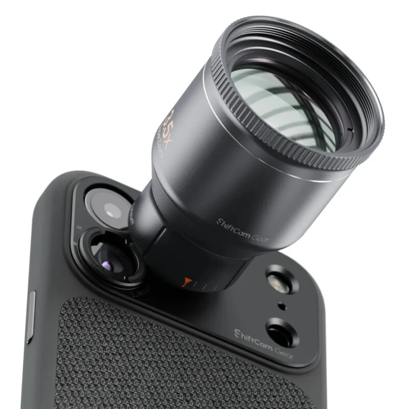 A ShiftCam Gear telephoto lens attachment is mounted onto the camera array of a smartphone in a textured black case.