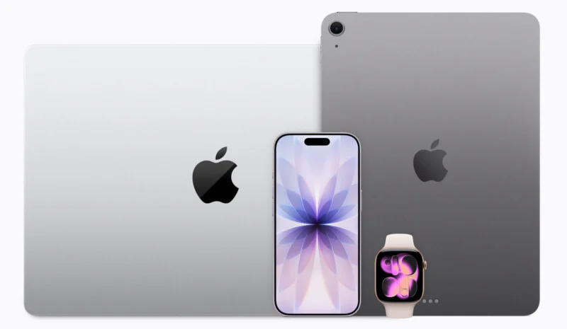 A silver laptop, a smartphone with a floral wallpaper, a dark gray tablet, and a smartwatch with a pink band are arranged against a white background.