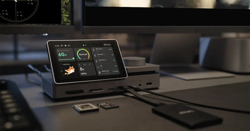 A docking station with a touchscreen display sits on a desk, showing system status, power usage, and connected devices.