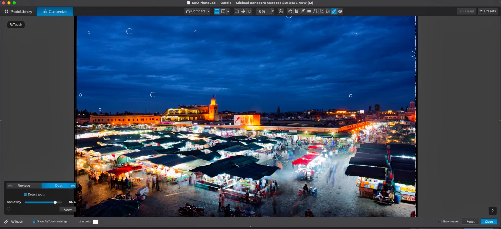 A software interface displays a night market scene with several circular retouching markers overlaid on the sky and stalls.