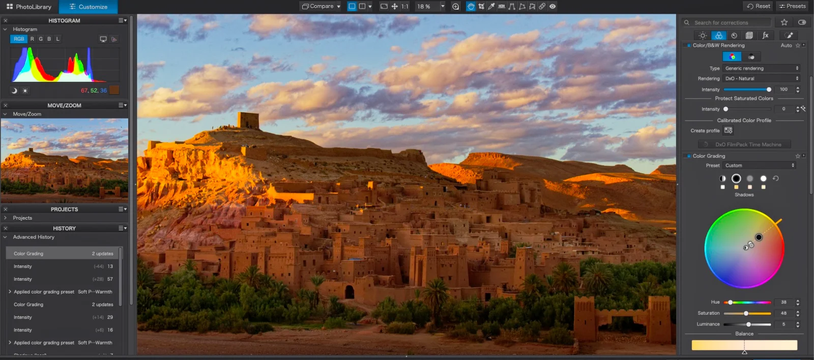 A computer screen displays a photo editing interface showing a landscape of a desert village at sunset, with a color grading wheel and histogram panels visible.