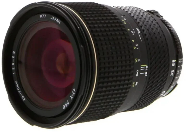A black Tokina AT-X PRO 28-70mm f/2.6-2.8 camera lens with a 77mm filter thread, shown from a side-angled perspective.