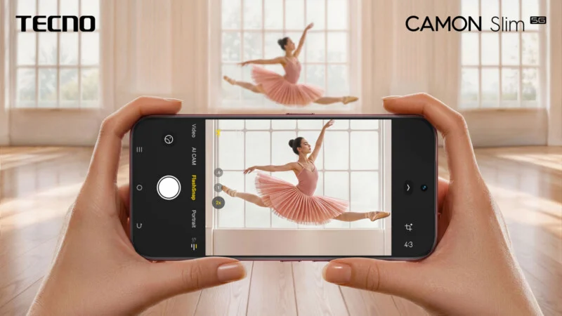 A pair of hands holds a smartphone displaying a camera interface, showing a ballerina mid-leap on the screen.