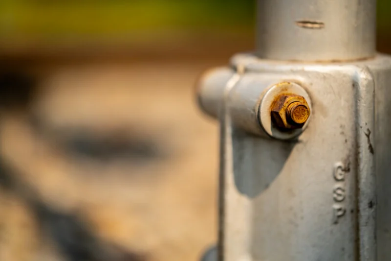 A close-up view of a rusty bolt and nut securing a metal pipe fitting, with the letters "GSP" embossed on the side.