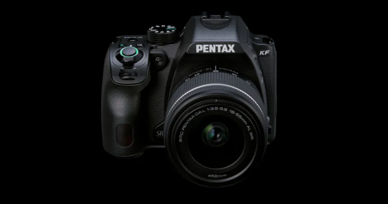 A black Pentax KF DSLR camera with an 18-55mm lens attached, centered against a solid black background.