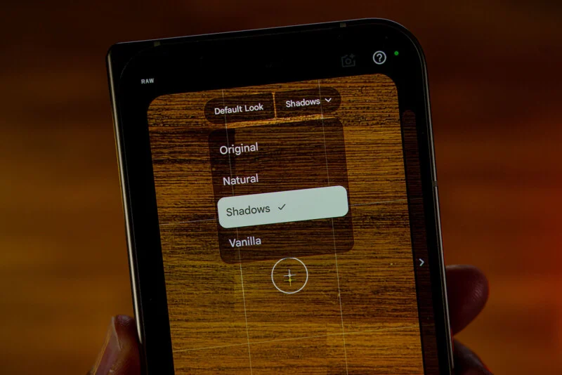A smartphone screen displays a photo editing interface with a dropdown menu showing options for Original, Natural, Shadows, and Vanilla, with Shadows currently selected.
