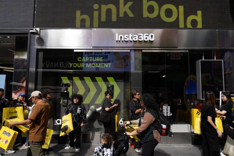 People walk past an Insta360 storefront in Times Square with a large "hink bold" sign above the entrance.