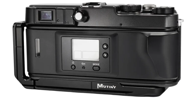 A black film camera back with a digital LCD screen, control buttons, and a "MUTINY" label at the bottom.