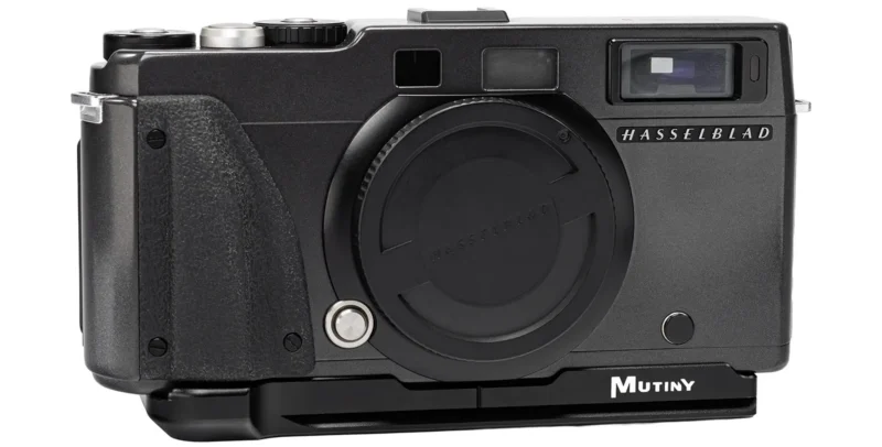A black Hasselblad camera body with a lens cap attached, featuring a Mutiny base plate mounted on the bottom.