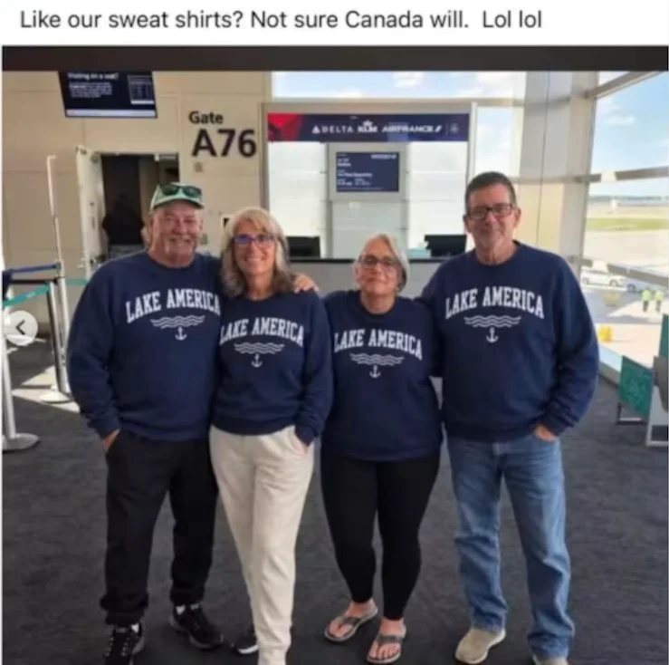 Four people stand in an airport terminal at Gate A76 wearing matching navy blue sweatshirts that say "LAKE AMERICA" with an anchor icon.