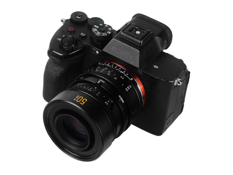 A black mirrorless digital camera with a 50mm prime lens attached, viewed from a high angle against a white background.