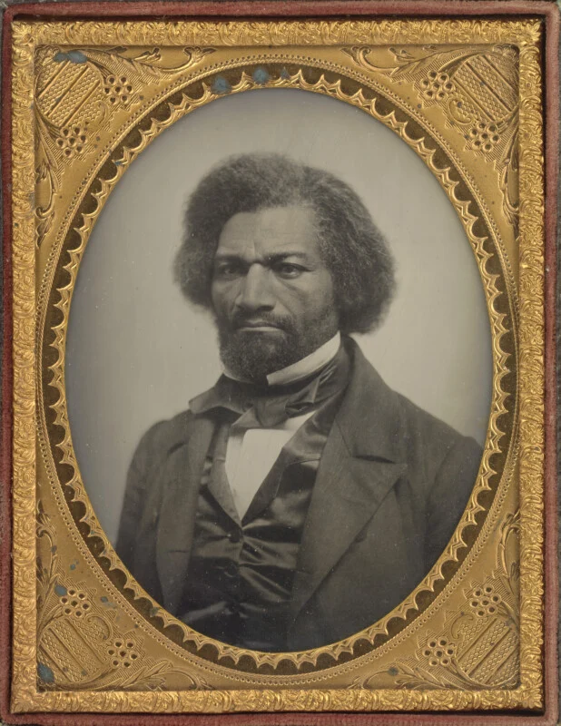 A daguerreotype portrait of Frederick Douglass, featuring his head and shoulders framed in an ornate, oval gold-colored border.