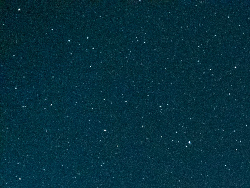 A dark blue, grainy background filled with numerous small, scattered white dots resembling stars.